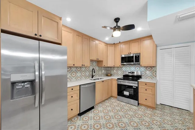 a kitchen with stainless steel appliances granite countertop a refrigerator a stove a sink and white cabinets with wooden floor