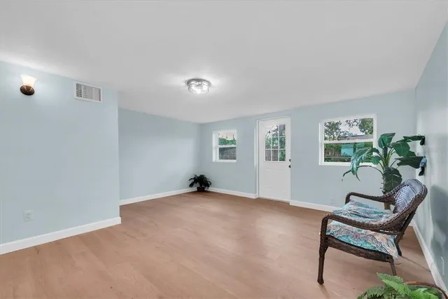 a view of an empty room with window and wooden floor