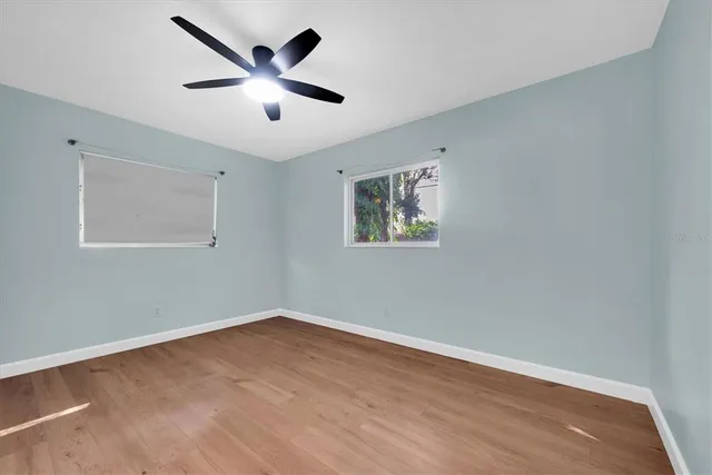 an empty room with wooden floor and ceiling fan