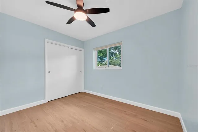 an empty room with ceiling fan and window