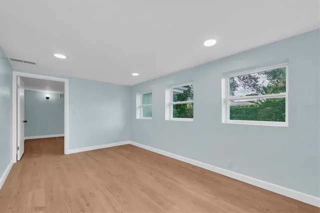 a view of an empty room with a window and a kitchen