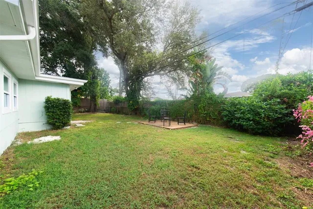 a view of a backyard with potted plants and large trees