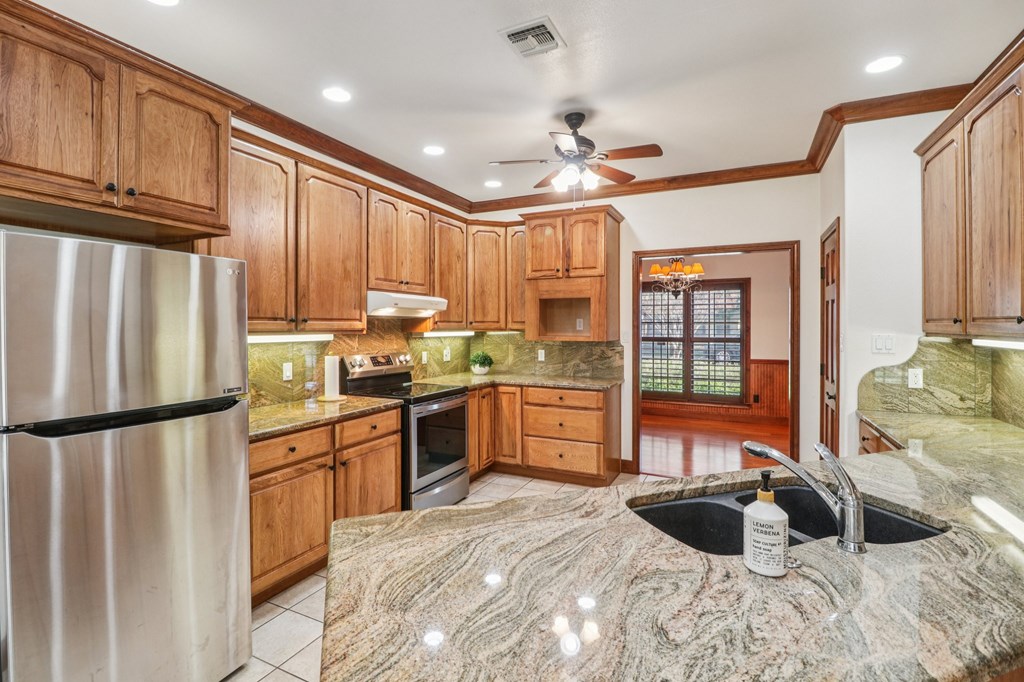 802 Ave C Fredericksburg, TX 78624 - Photo 8 of 22 a kitchen with stainless steel appliances granite countertop a refrigerator a stove a sink and a refrigerator with wooden floor