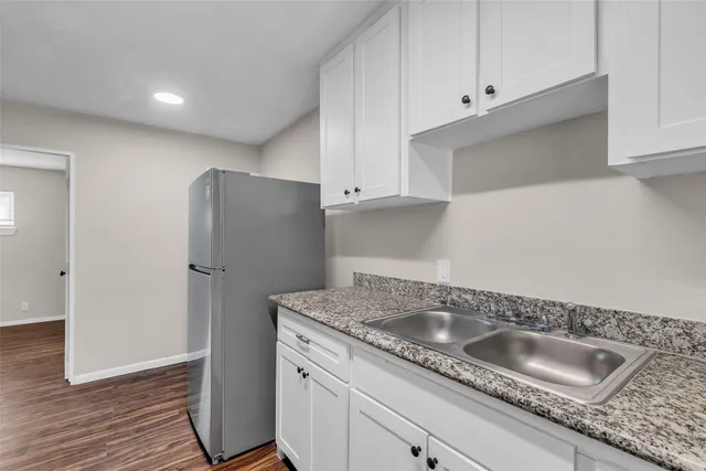 a kitchen with granite countertop a sink and refrigerator