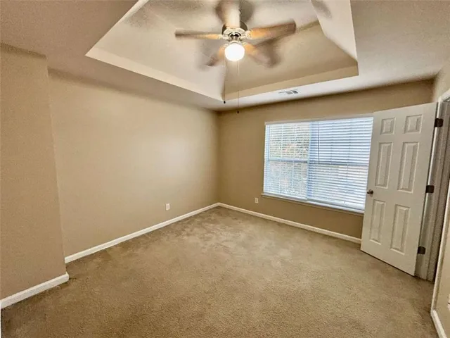 an empty room with a ceiling fan and carpet