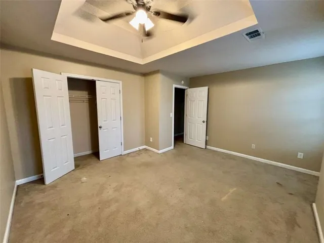 an empty room with a ceiling fan and carpet