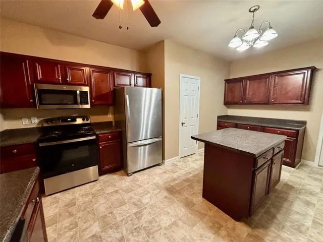a kitchen with stainless steel appliances granite countertop a stove refrigerator and a microwave oven