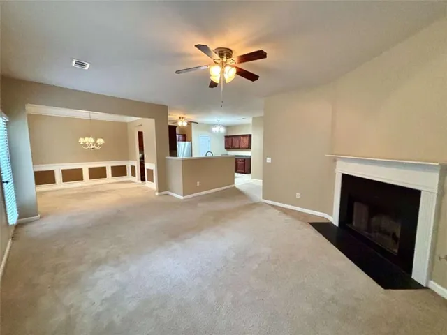 a view of a livingroom with a fireplace a ceiling fan and windows