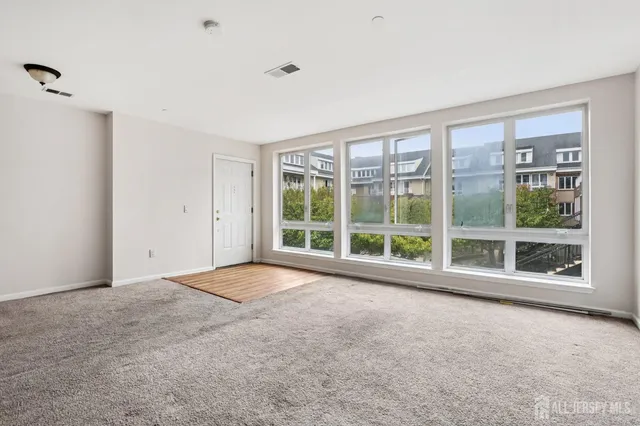 a view of an empty room with a large window and wooden floor