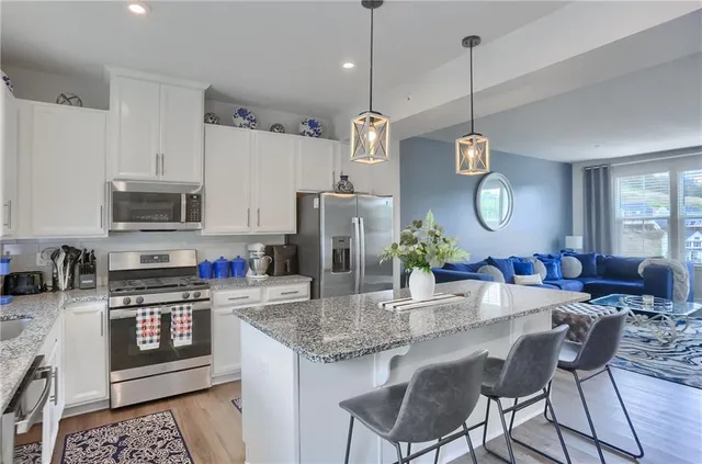 a kitchen with stainless steel appliances granite countertop a sink a stove a refrigerator cabinets and chairs