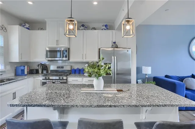 a kitchen with stainless steel appliances granite countertop a sink refrigerator stove and microwave