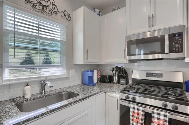 a kitchen with stainless steel appliances granite countertop a sink a stove and a microwave