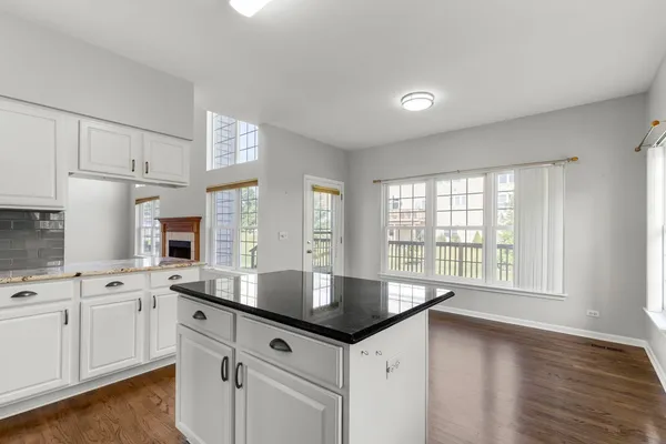 a kitchen with granite countertop a sink and white cabinets with wooden floor
