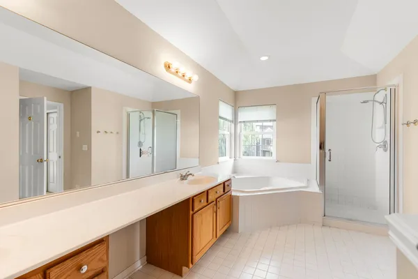 a spacious bathroom with a shower a large mirror and a bathtub