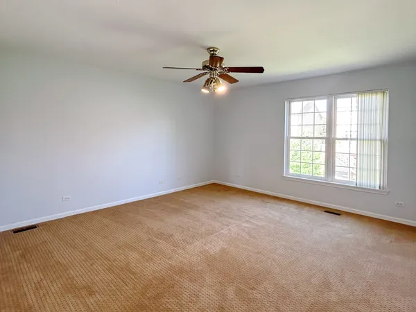 an empty room with windows and fan