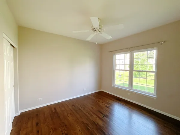 an empty room with wooden floor fan and windows