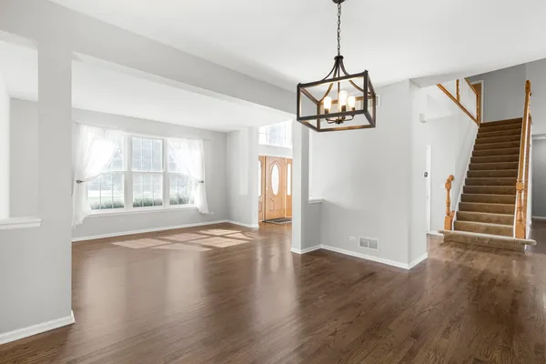 a view of an empty room with wooden floor and windows