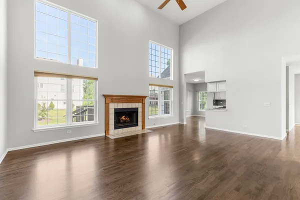 an empty room with wooden floor a fireplace and windows