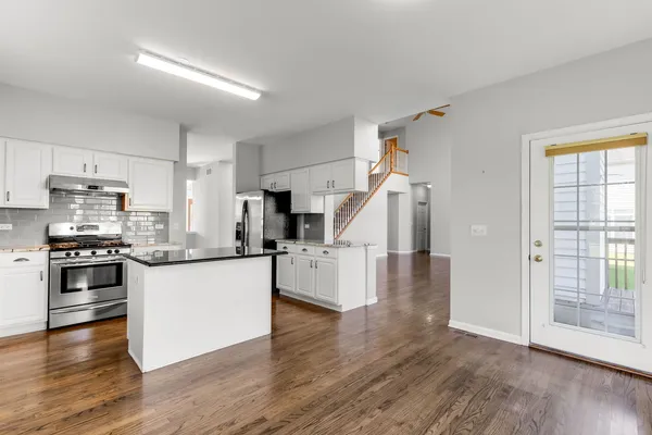 a kitchen with granite countertop a refrigerator and wooden floor