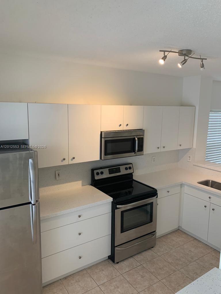 6975 Blacksmith Way Lake Worth, FL 33467 - Photo 5 of 21 a kitchen with a refrigerator stove and white cabinets