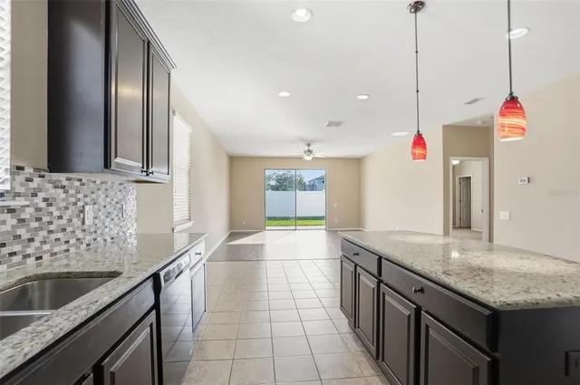 a kitchen with granite countertop a sink a counter top space and cabinets