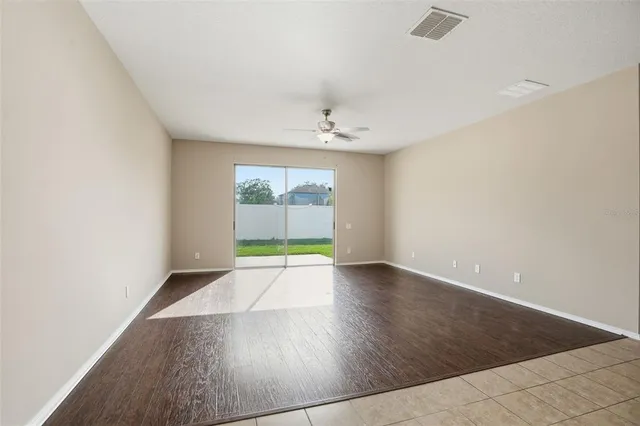 an empty room with wooden floor mirror and windows