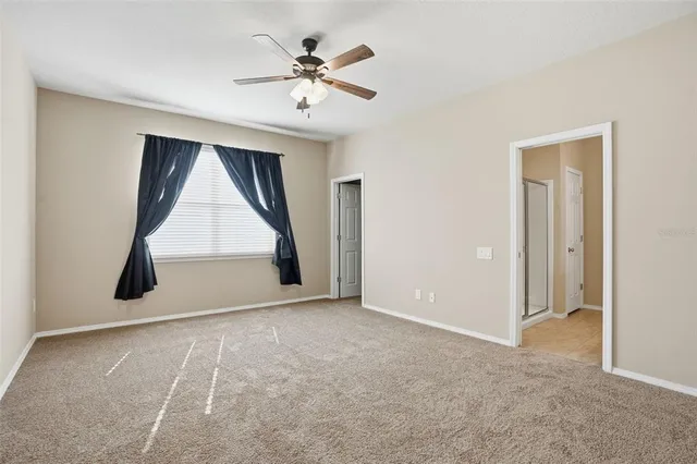 an empty room with ceiling fan and window