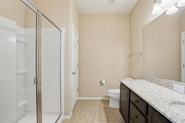a bathroom with a granite countertop sink a toilet and shower