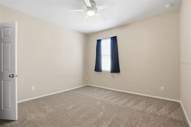 an empty room with a ceiling fan and a window