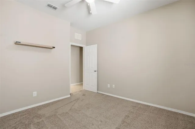 an empty room with a ceiling fan and a window