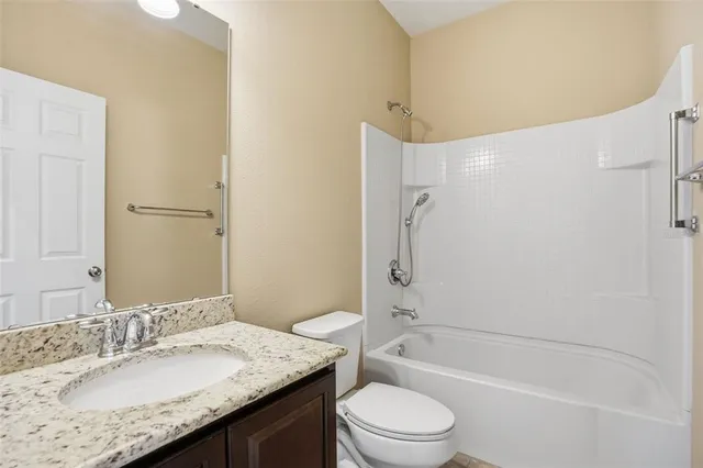 a bathroom with a granite countertop sink a toilet and shower