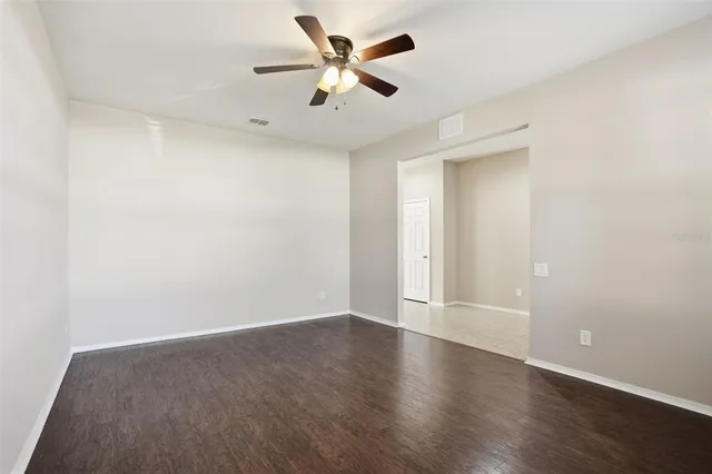 an empty room with wooden floor and a ceiling fan