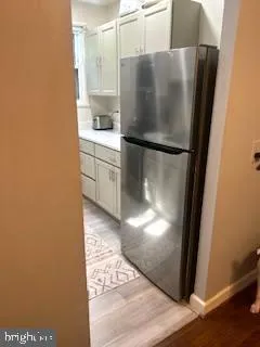 a view of a refrigerator in kitchen and an empty room