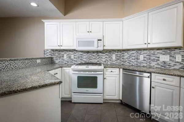 a kitchen with granite countertop white cabinets stainless steel appliances and a sink