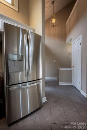 a view of a refrigerator in kitchen and an empty room