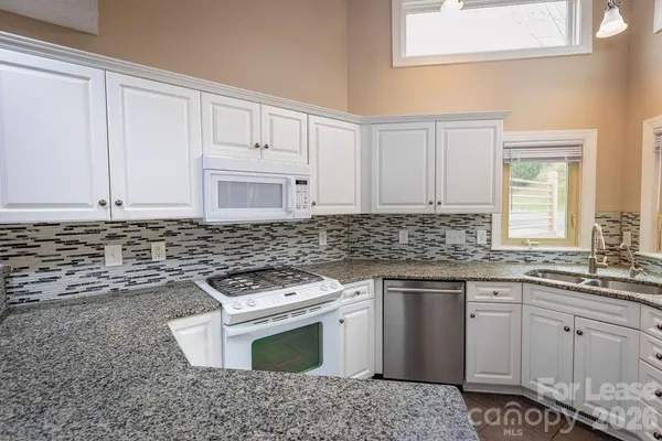 a kitchen with granite countertop white cabinets and white appliances