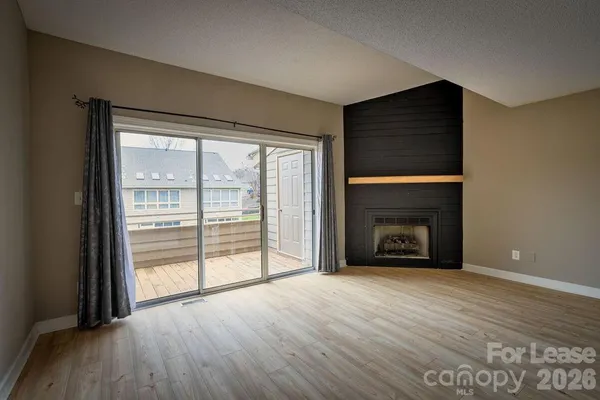 an empty room with wooden floor fireplace and windows