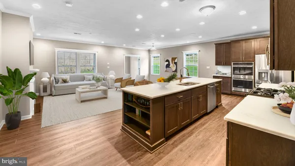 a kitchen with stainless steel appliances a sink a stove a refrigerator cabinets and wooden floor