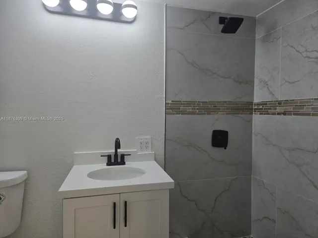 a bathroom with a sink a toilet and shower
