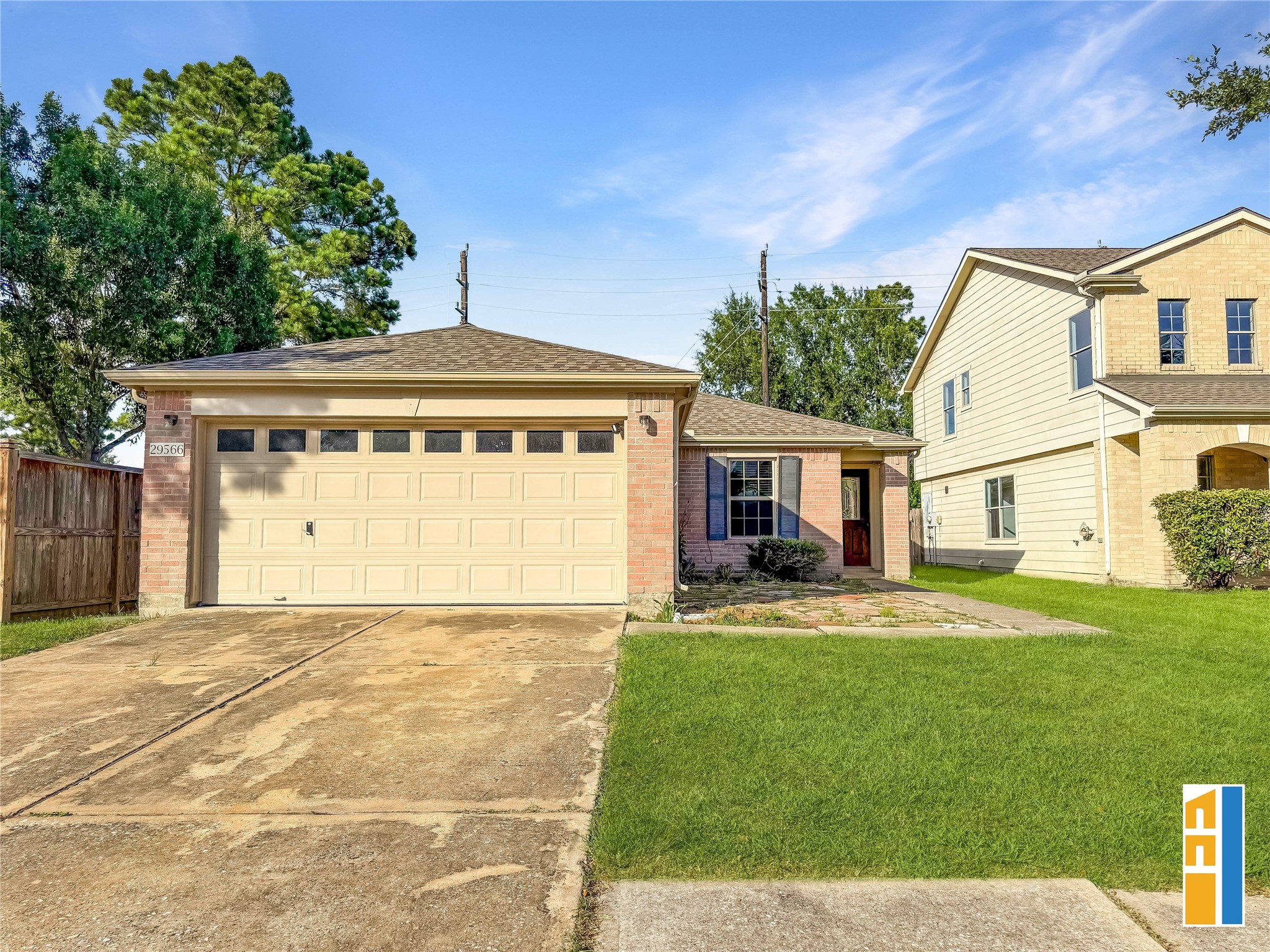 29566 North Legends Bend Drive Spring, TX 77386 - Photo 7 of 21 This photo features a charming single-story brick home with a two-car garage and a well-maintained lawn. A wooden fence provides privacy on one side, while mature trees offer shade and greenery. The home's exterior is inviting, with a welcoming front entrance.
