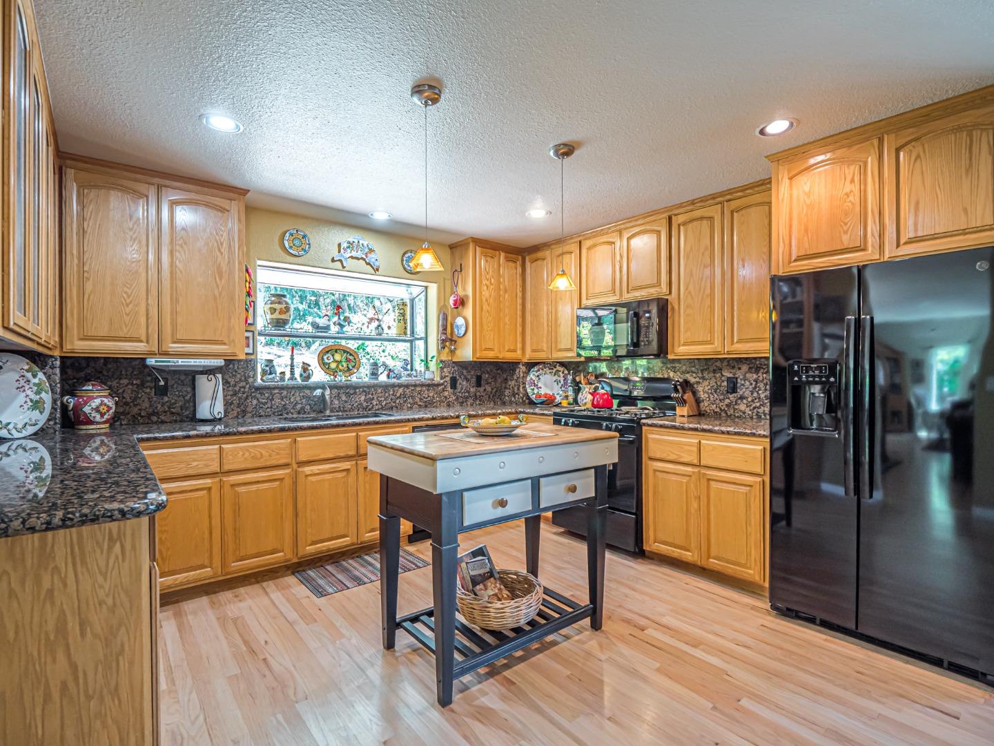 394 Hames Road Corralitos, CA 95076 - Photo 11 of 39 a kitchen with granite countertop a stove a sink dishwasher and a refrigerator with wooden floor