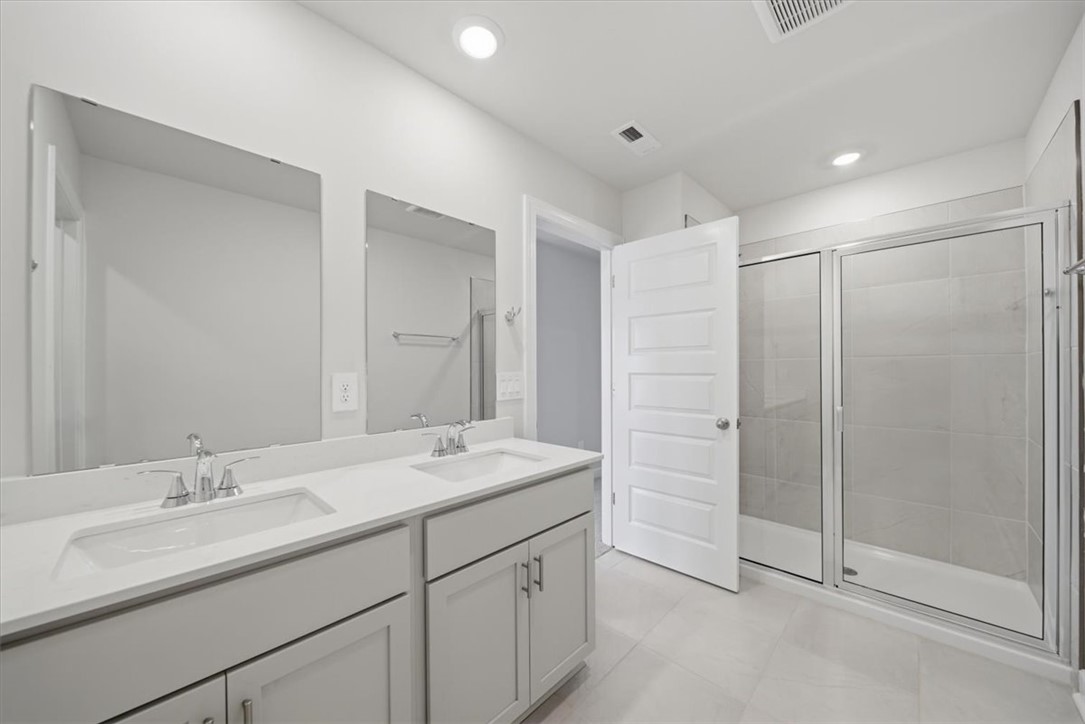 129 Kerwin Court Woodruff, SC 29388 - Photo 23 of 30 Dual vanities and a spacious glass-enclosed shower create a practical, uncluttered bathroom layout.