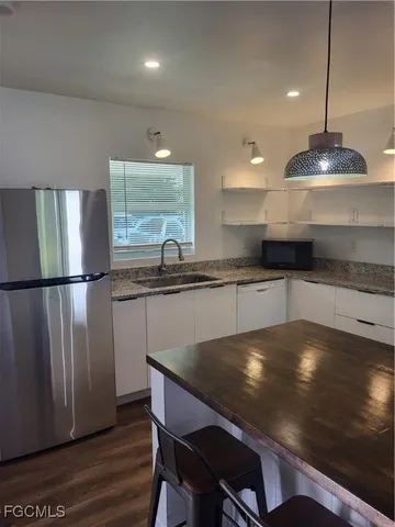 a kitchen with granite countertop a sink a counter space appliances and cabinets