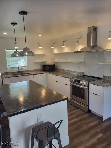 a kitchen with a stove a sink and a wooden floor