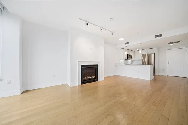 a view of a big room with wooden floor and a kitchen