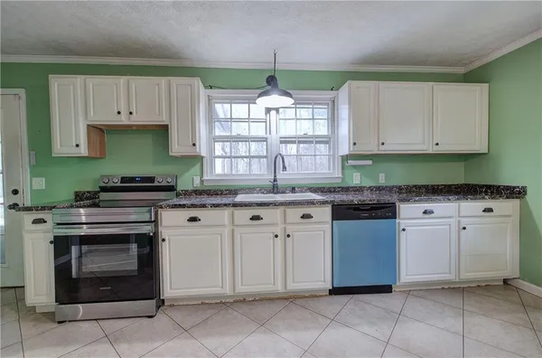 a kitchen with granite countertop a stove sink and cabinets