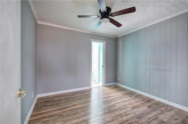 an empty room with wooden floor fan and windows