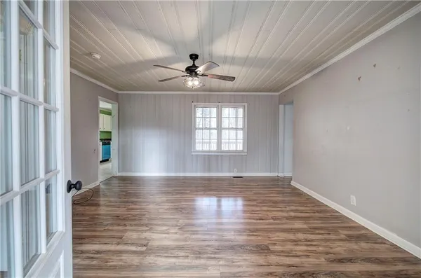 a view of an empty room with window and wooden floor