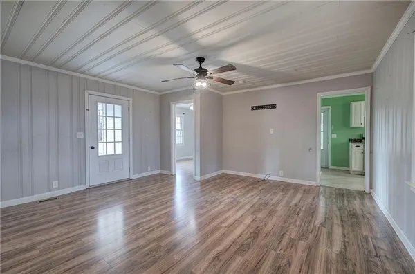 a view of an empty room with wooden floor and a ceiling fan