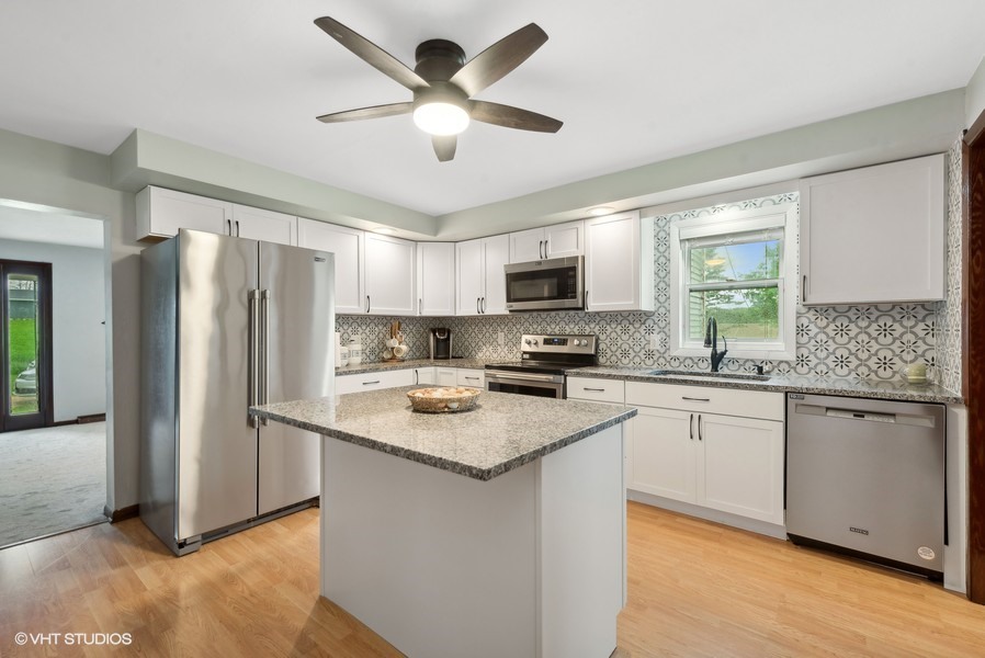 11719 Engelhardt Road Harvard, IL 60033 - Photo 5 of 18 a kitchen with stainless steel appliances granite countertop a stove a sink a refrigerator a microwave oven with cabinets and wooden floor